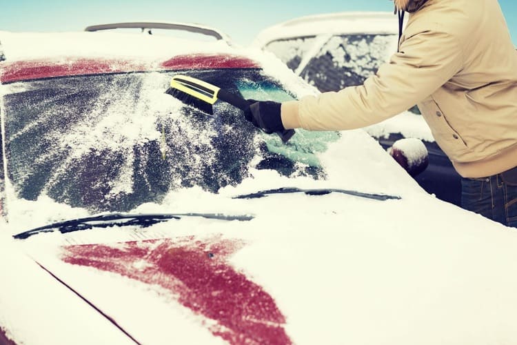 Un hombre elimina la nieve del parabrisas de un automóvil con un cepillo